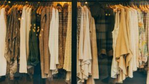 A rack of beige, white, and neutral-toned clothing hanging on wooden hangers.