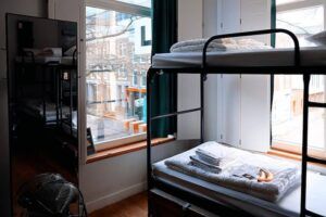 Metal bunk beds with white bedding in a room with a large window.