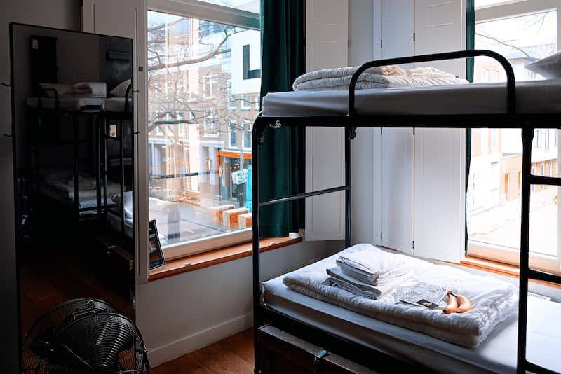 Metal bunk beds with white bedding in a room with a large window.