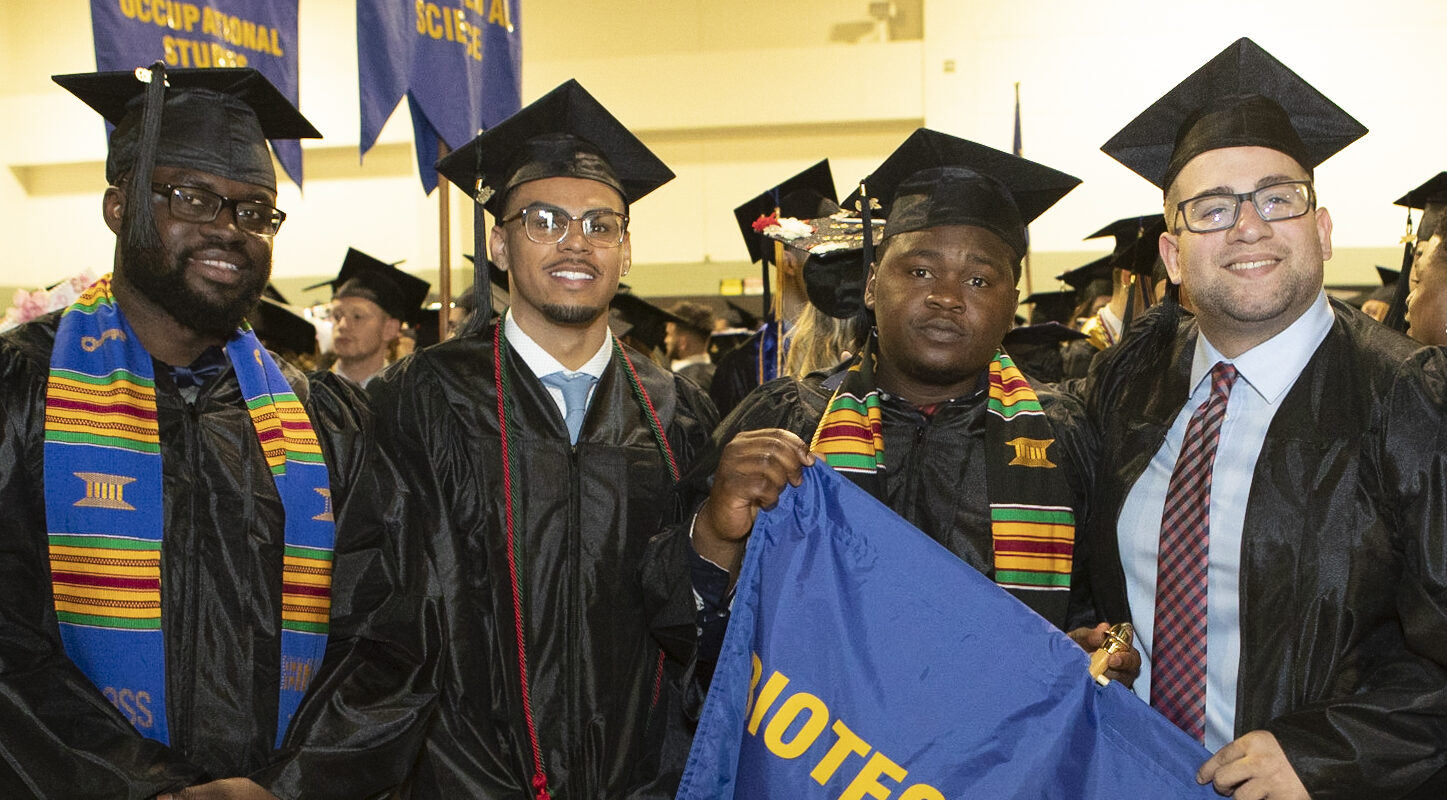 Biotechnology honors students hold "Biotechnology" flag at graduation