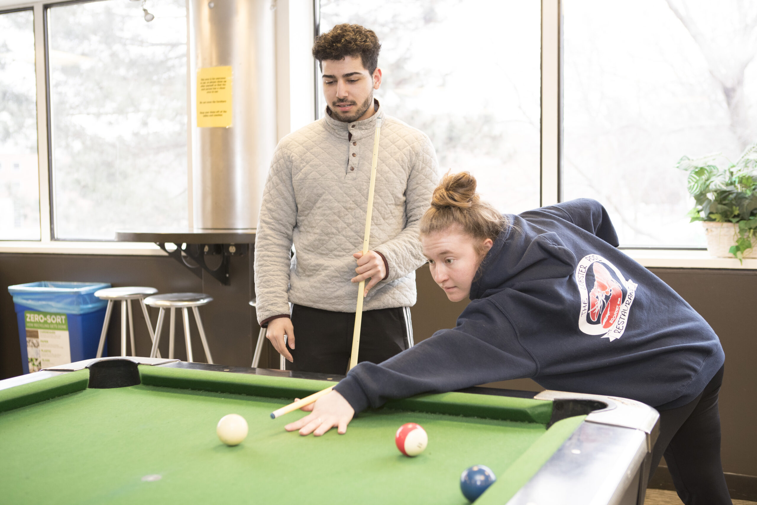2 Worcester State students playing pool in one of the residential communal lounges on campus