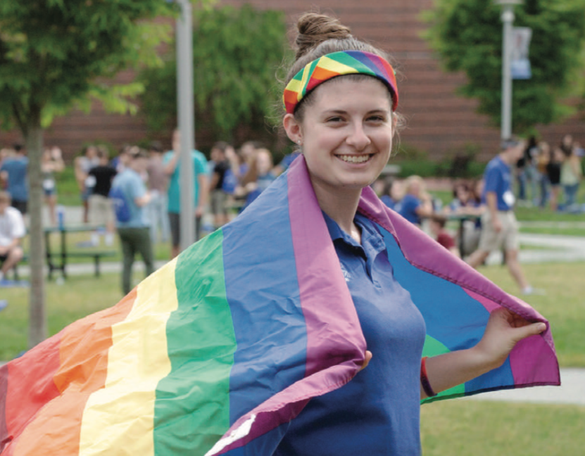 A ̳ State student wearing a pride flag on their shoulders like a cape