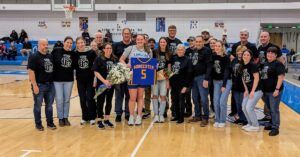 Student Abby St. Martin stands on basketball court with friends and family