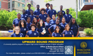 A diverse group of students wearing matching blue shirts pose together outdoors in front of a university building, representing the Upward Bound Program at Worcester State University.