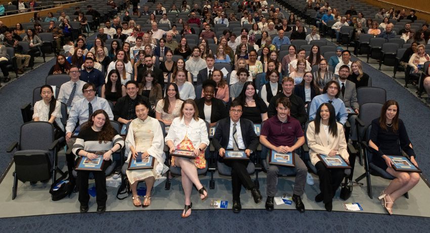 a large group of well-dressed people sitting, smiling