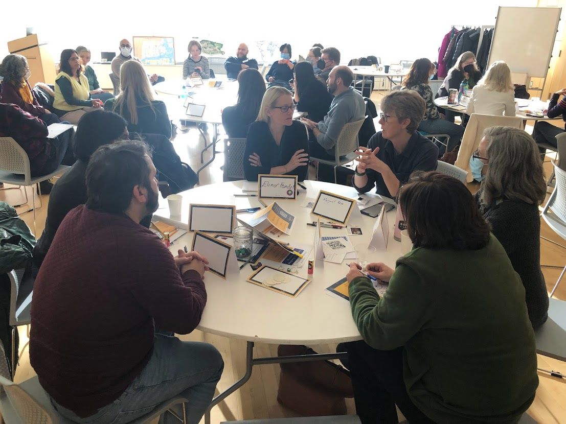 A group of Worcester State faculty members engaged in a collaborative discussion at a round table during a Winter Institute workshop session.