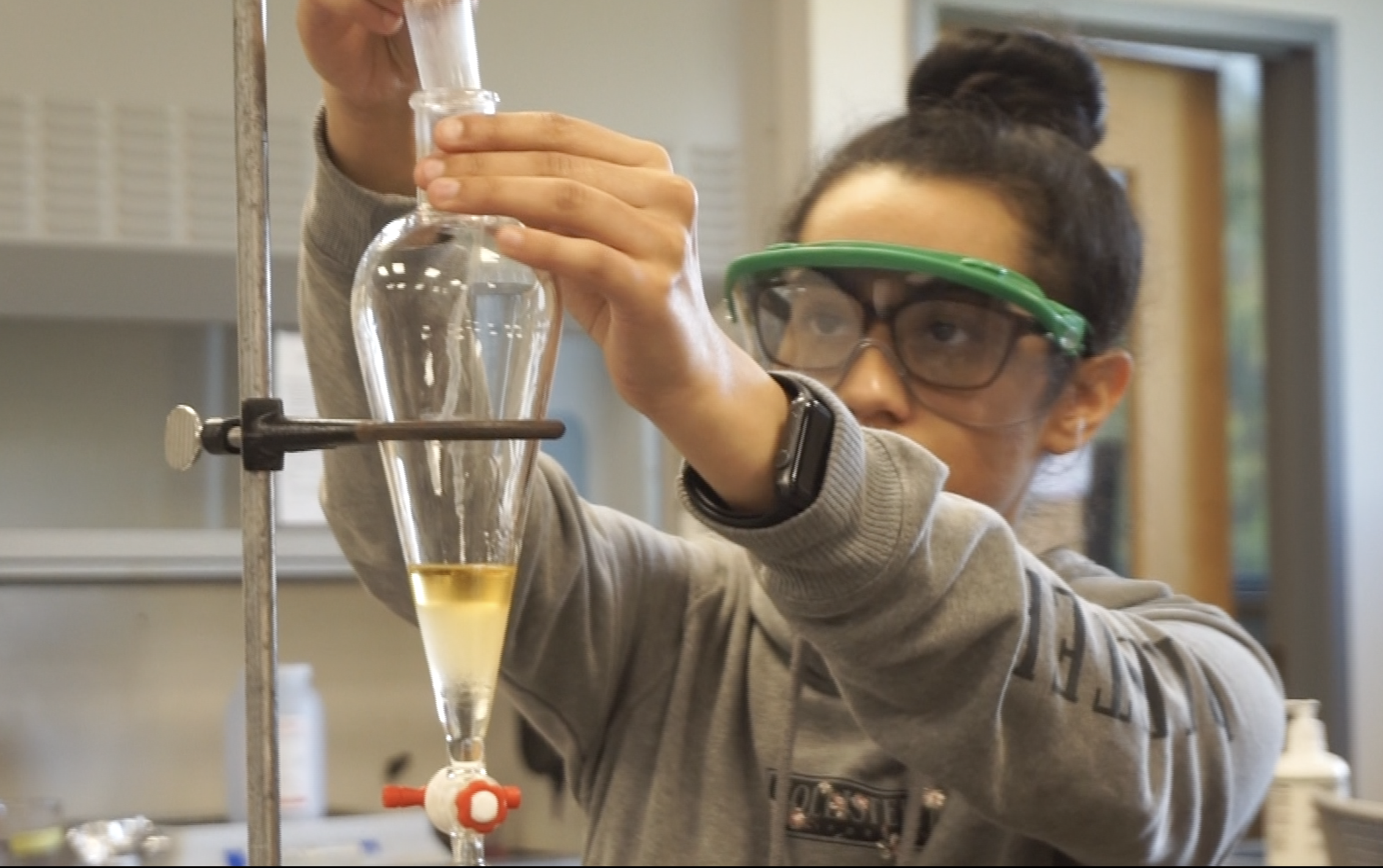Chemistry student drops liquid into a tubular beaker