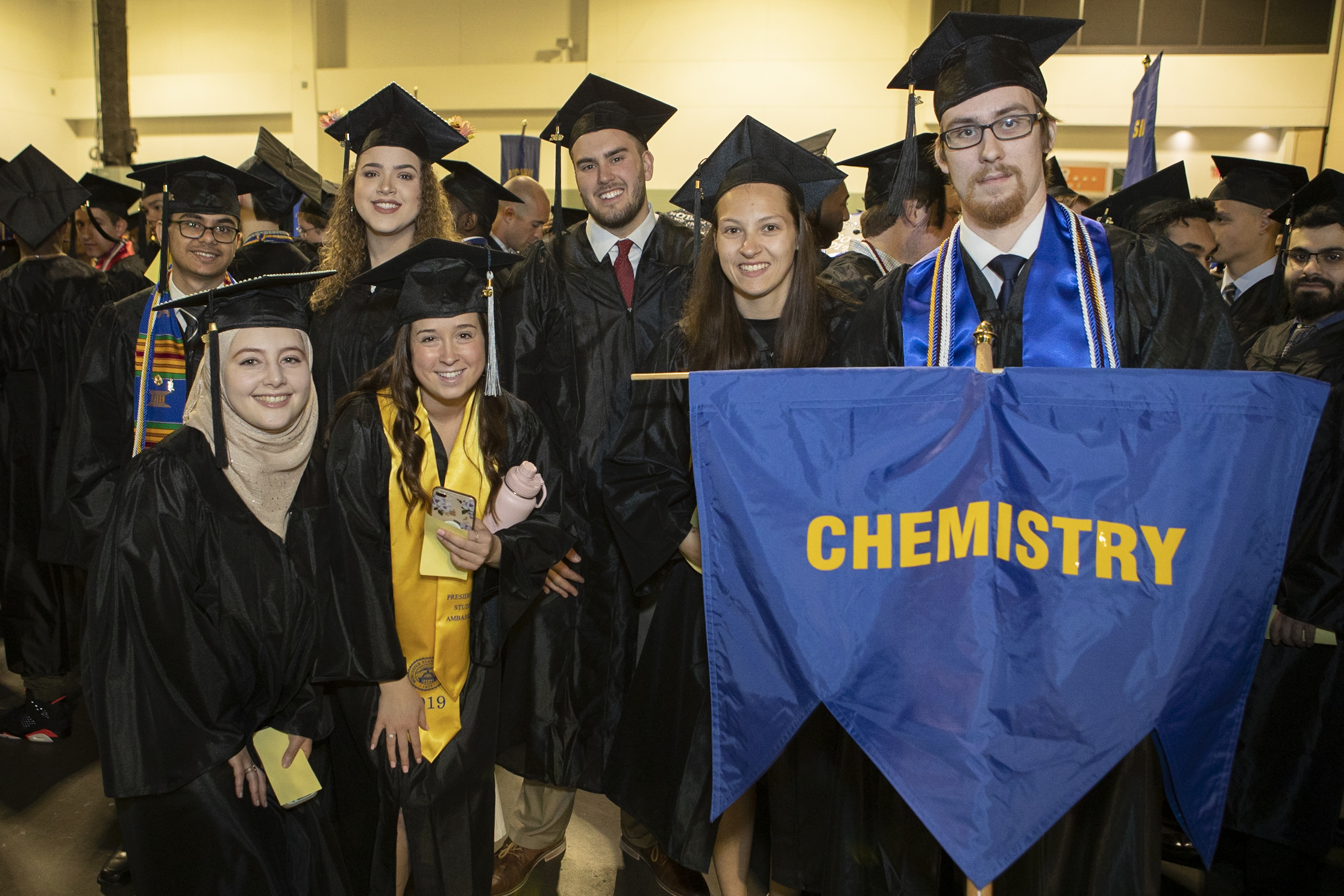 Chemistry honors students holding 'chemistry' flag during graduation