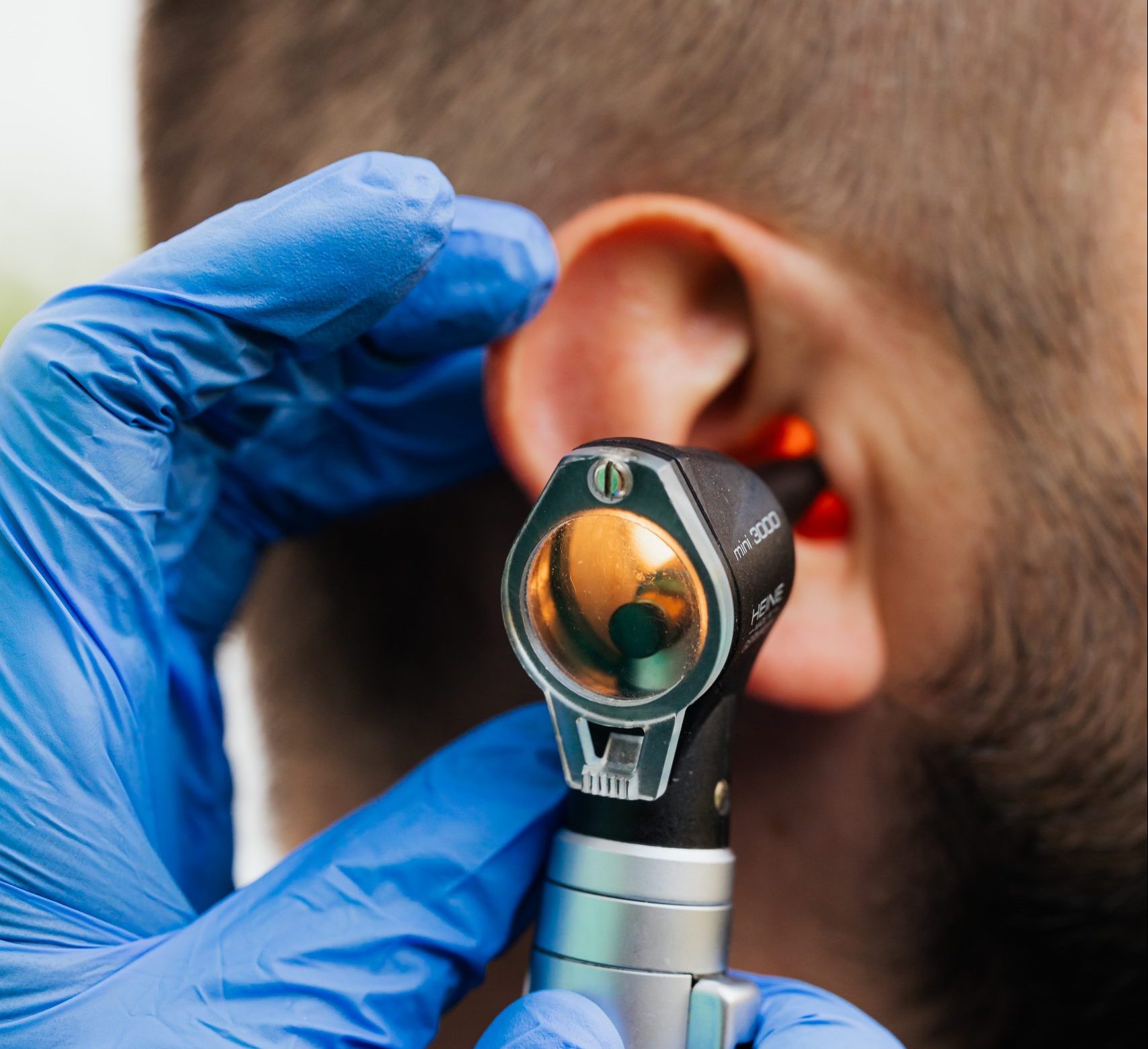 Audiologist examine patient's ear with otoscope