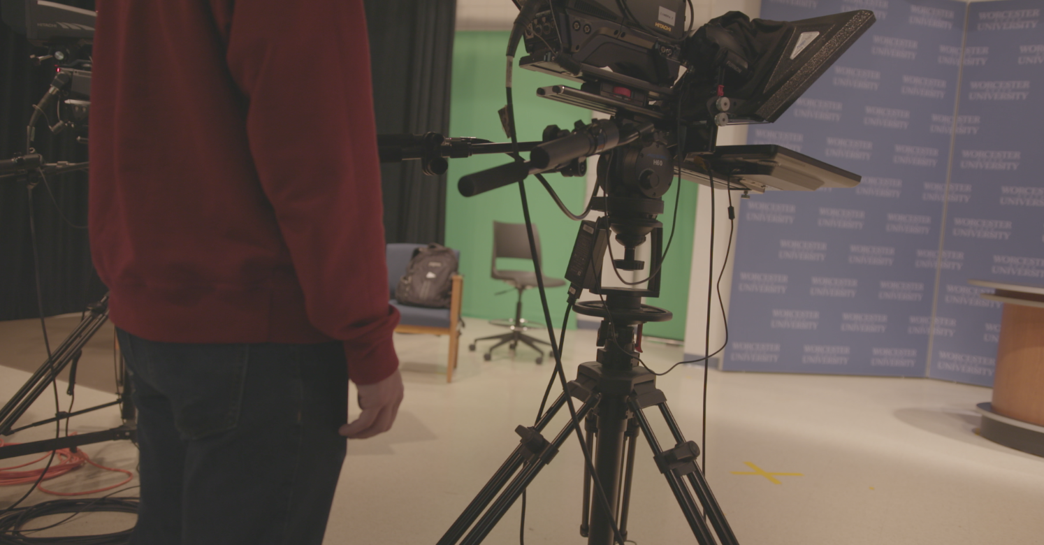 Communication student at Worcester State standing next to a camera in the TV Studio