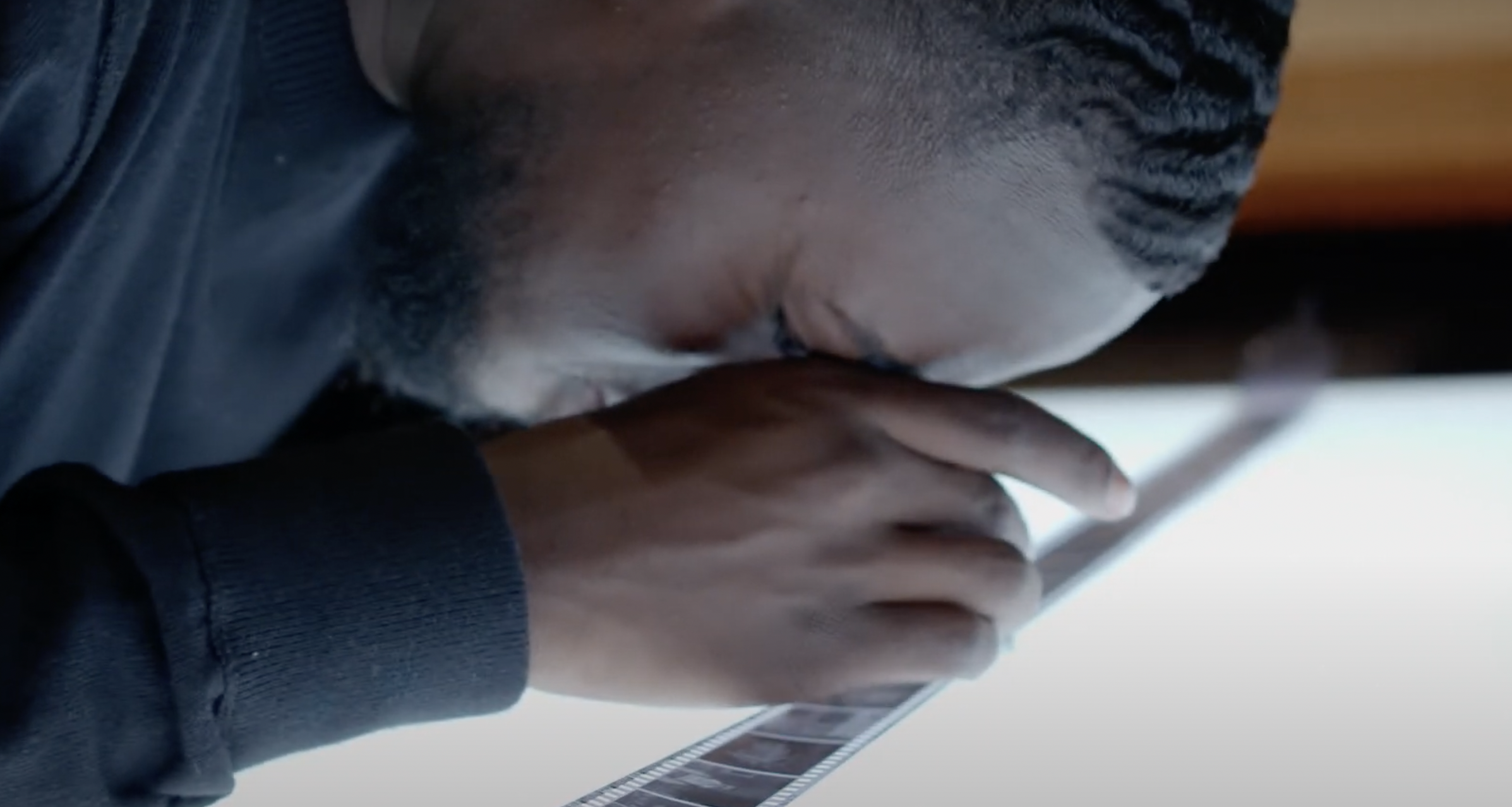 Communication Student examining a film strip with a magnifying glass