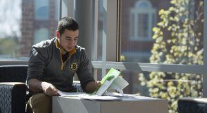Worcester State student sitting and reviewing folder of work