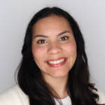 Woman with long dark hair and a nose piercing smiles at the camera against a plain white background, radiating the confidence and warmth often associated with Latino Education Institute Leadership.
