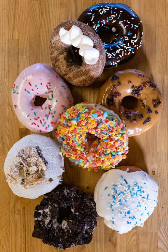 Close-up of a group of eight colorful doughnuts on a wood table