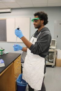 A student in a lab with lab apron and test tube
