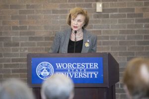Senator Chandler speaks from a podium with the Worcester State seal on it