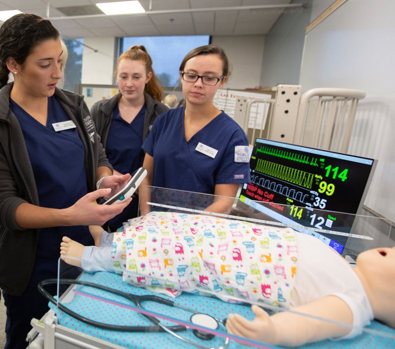 Three nursing students training with a medical dummy
