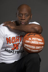 Al Pettway looks into the camera while leaning his elbow on a basketball balanced on his knee