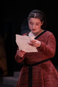 Roan Testa, in character as Lady Macbeth, holds out a letter she is reading.