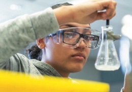 A college student stirring liquid in a science beaker