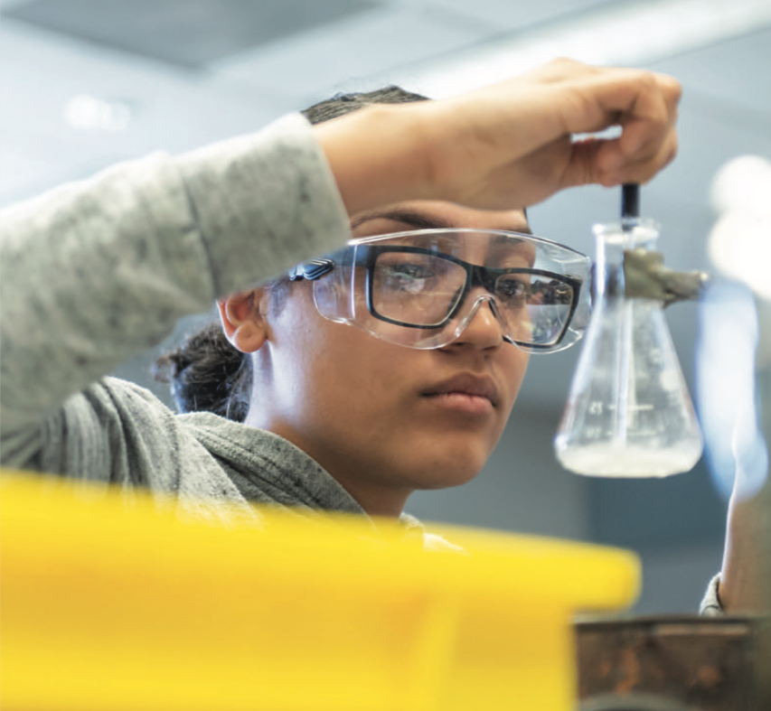 A college student stirring liquid in a science beaker