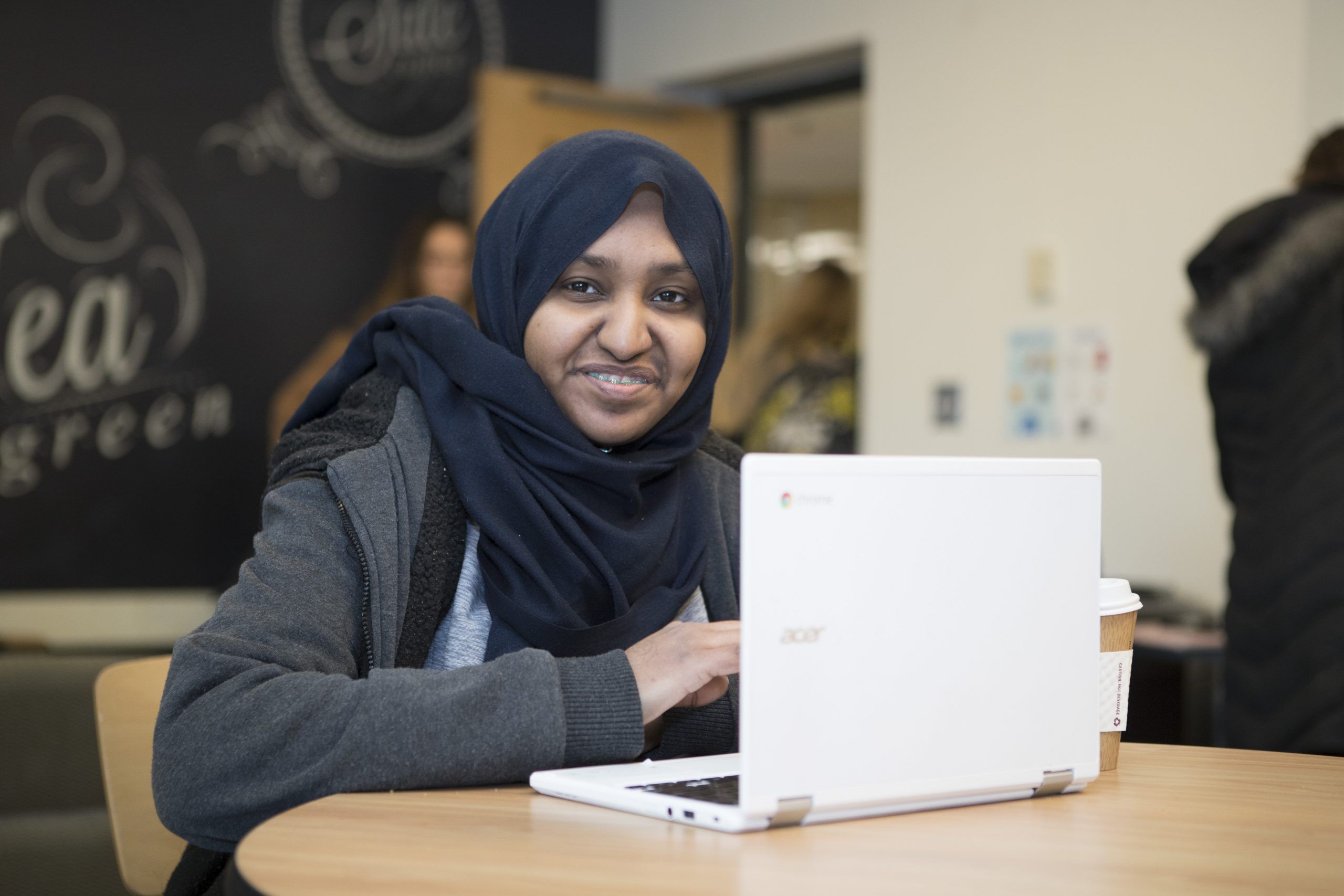 A smiling Worcester State student working on their laptop