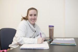 Aw smiling Worcester State student writing in their notebook