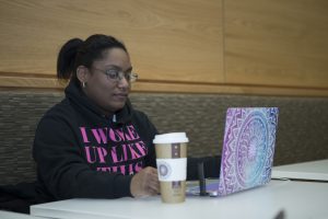 A Worcester State student working on their laptop while drinking coffee