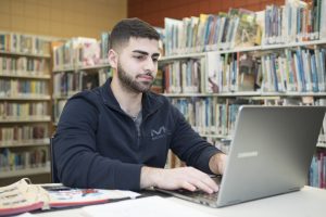 A Worcester State student working on their laptop in the library on campus