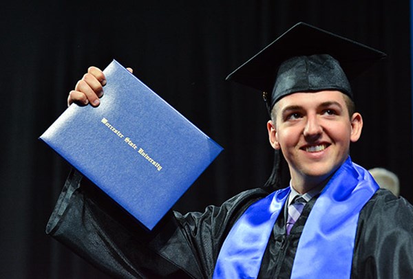 A proud Worcester State graduate holding up their diploma