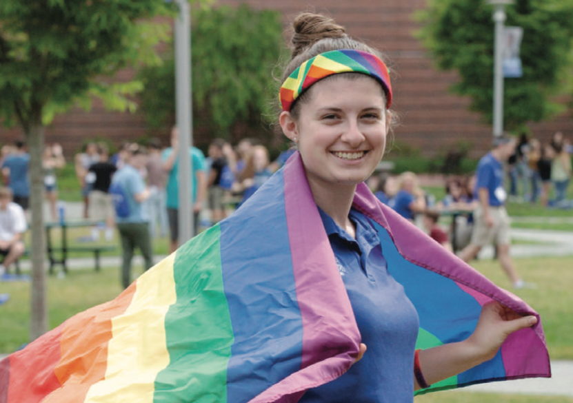 A student wearing a rainbow flag on their back