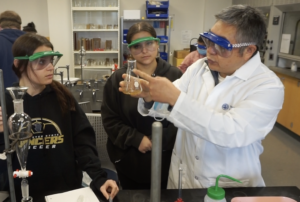 A Worcester State professor teaching students about chemistry in a lab