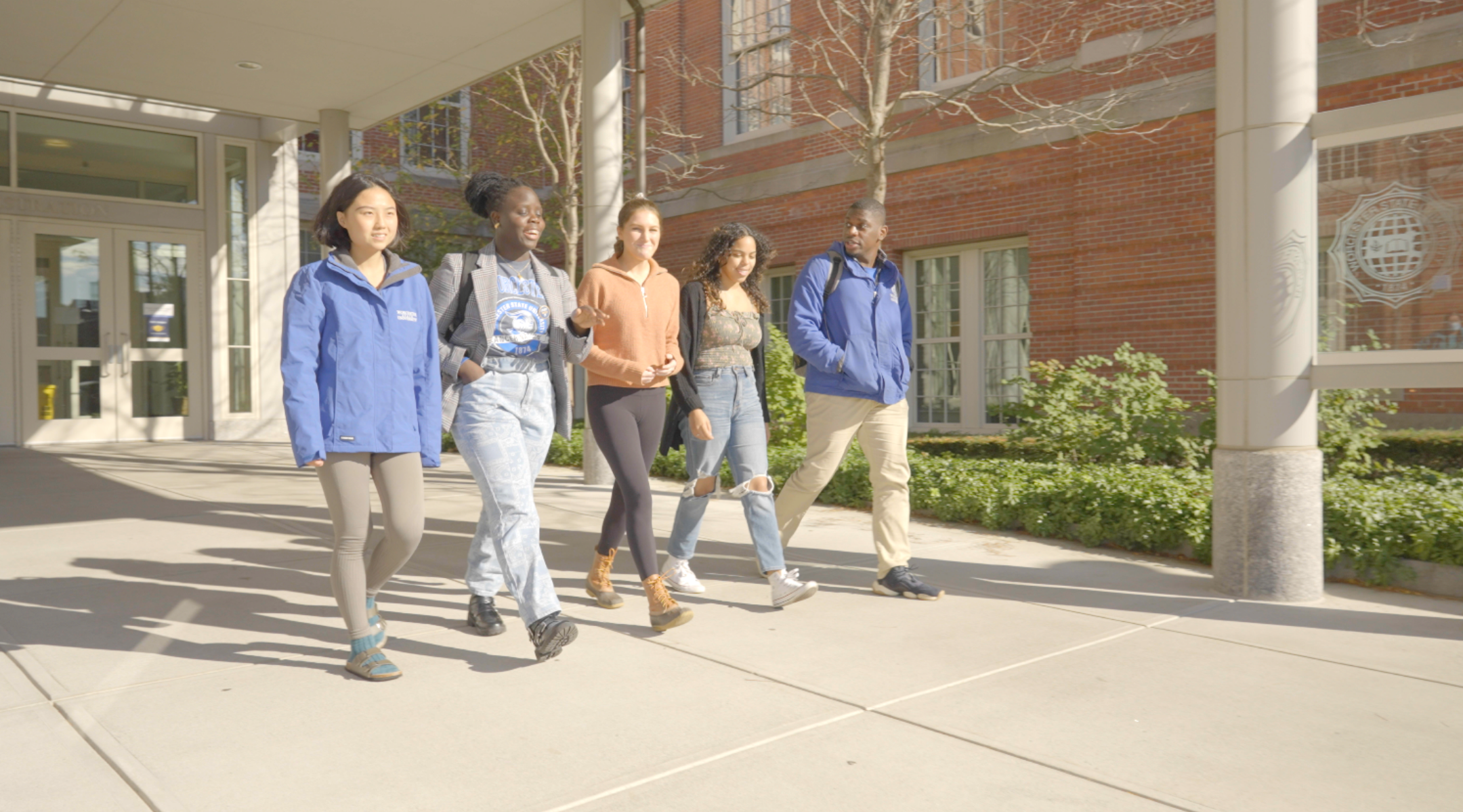 5 worcester state students talking together as they walk through campus