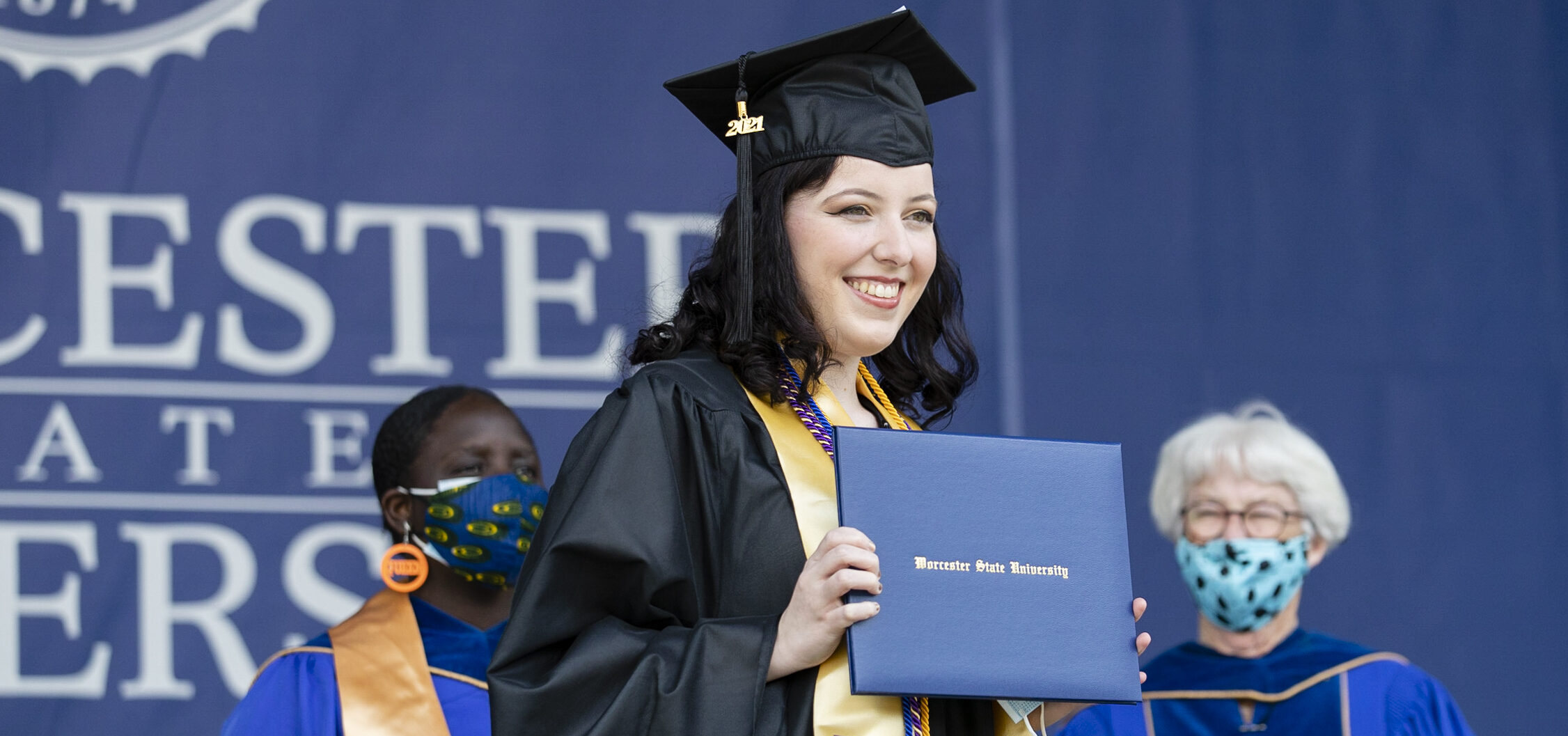 A student at the Worcester State University Graduation Ceremony showing off her diploma on stage