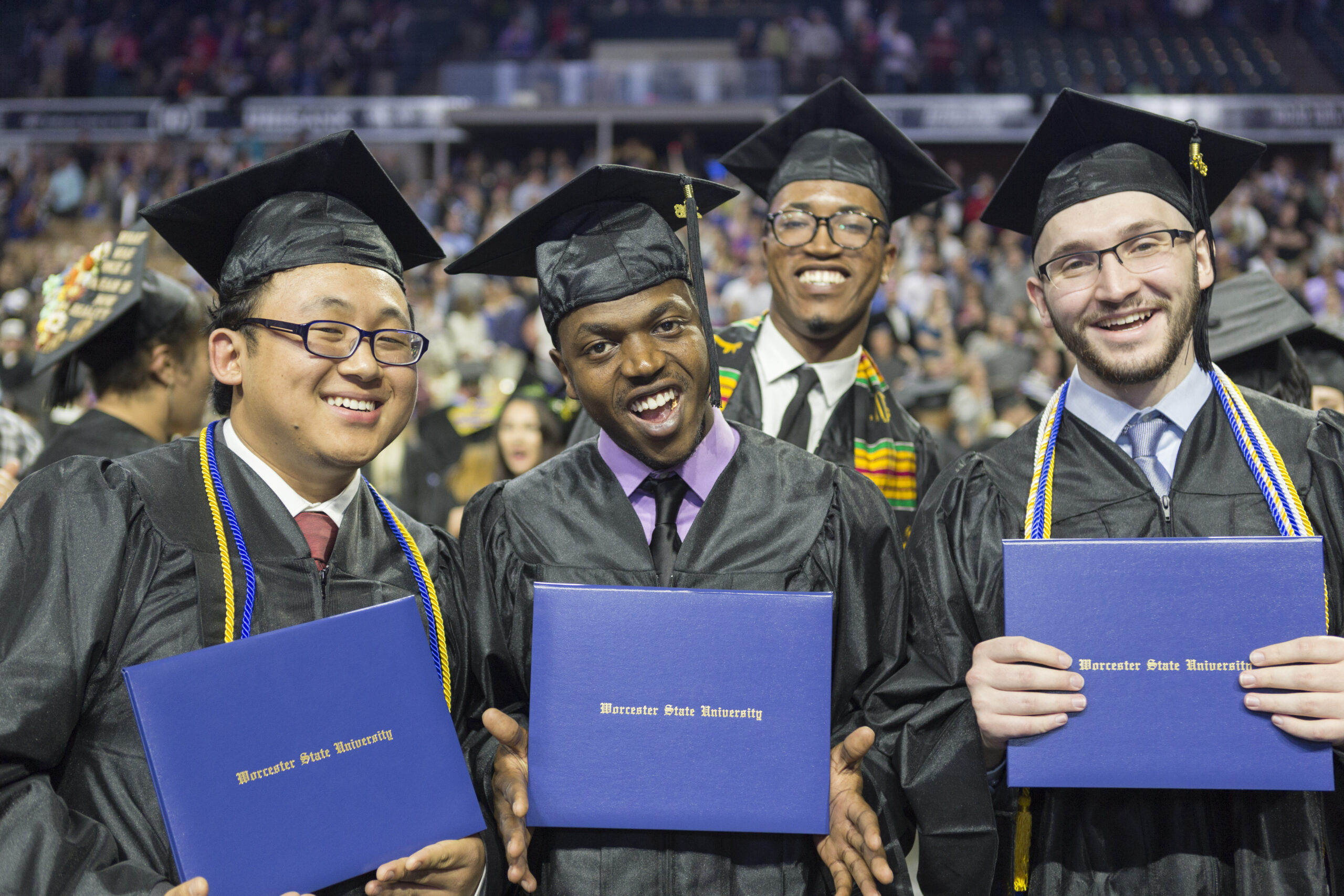 4 Proud Worcester State graduates holding up their diplomas