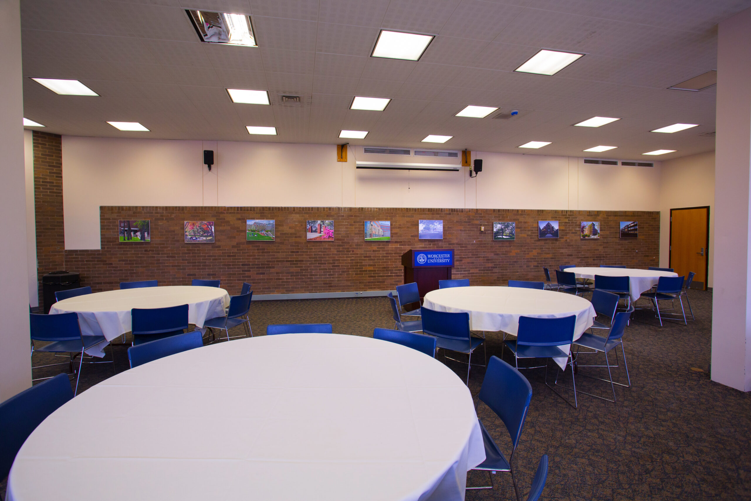 An events room with 4 tables set up with blue chairs and a podium