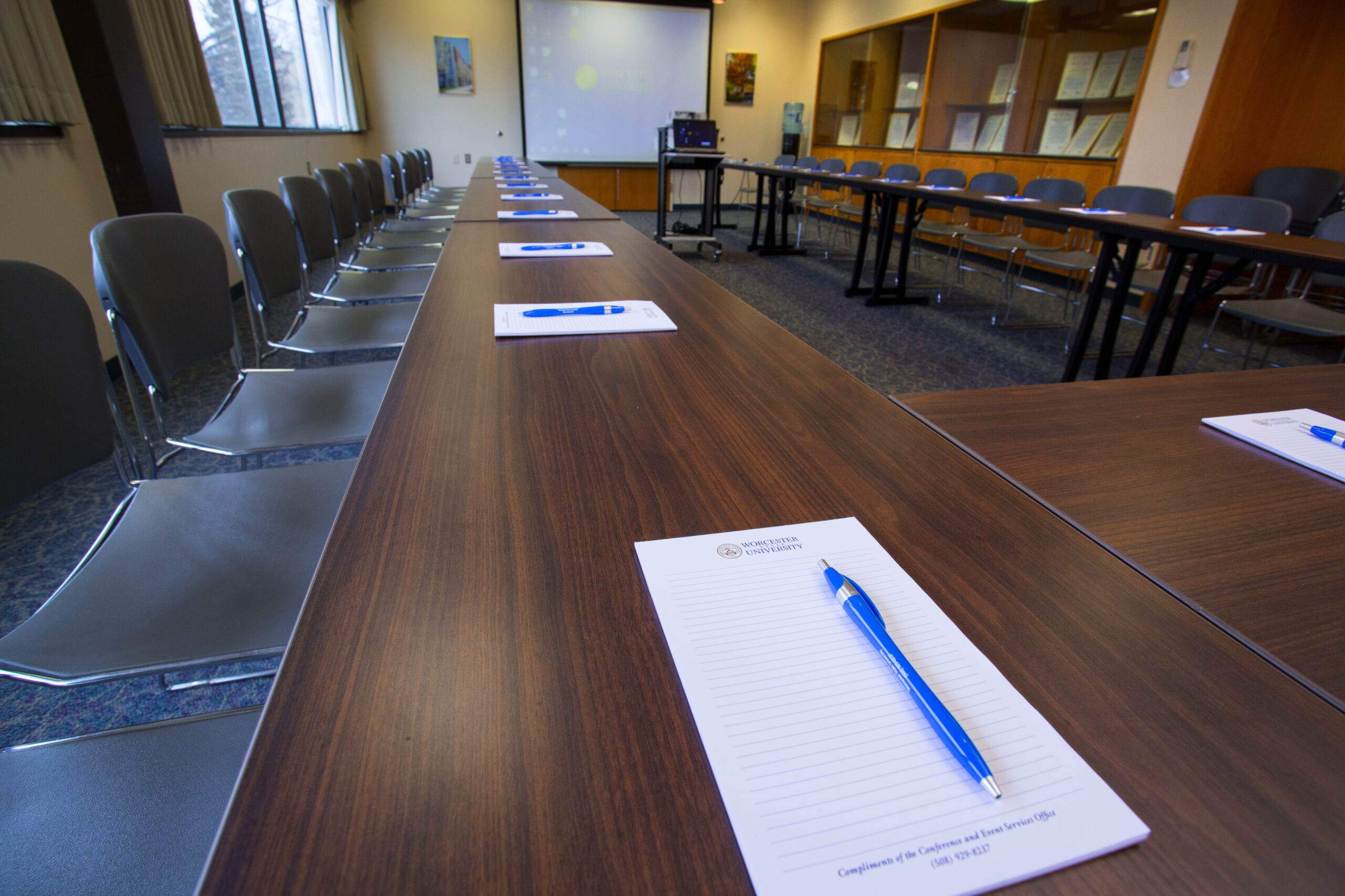 An empty Worcester State conference room with pads of paper and pens at each seat