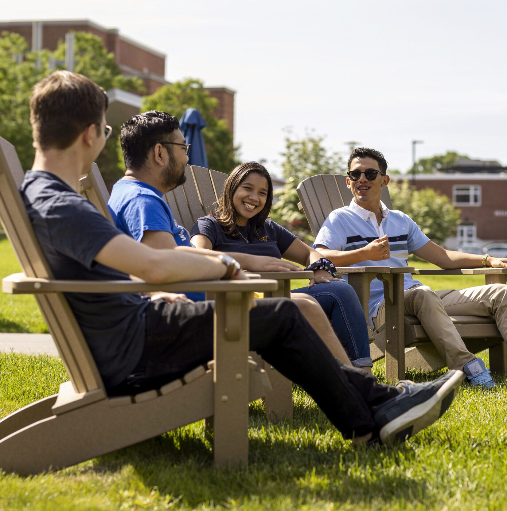 4 Worcester state students sitting in Adirondack chairs outside on campus