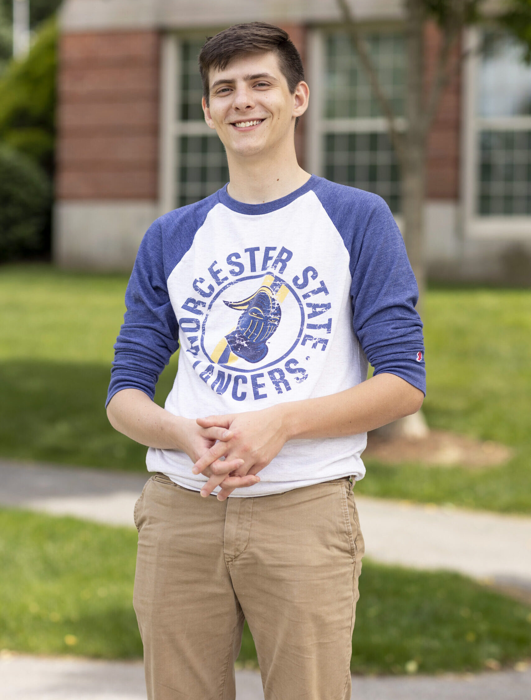 A smiling Worcester State student standing outside holding their hands