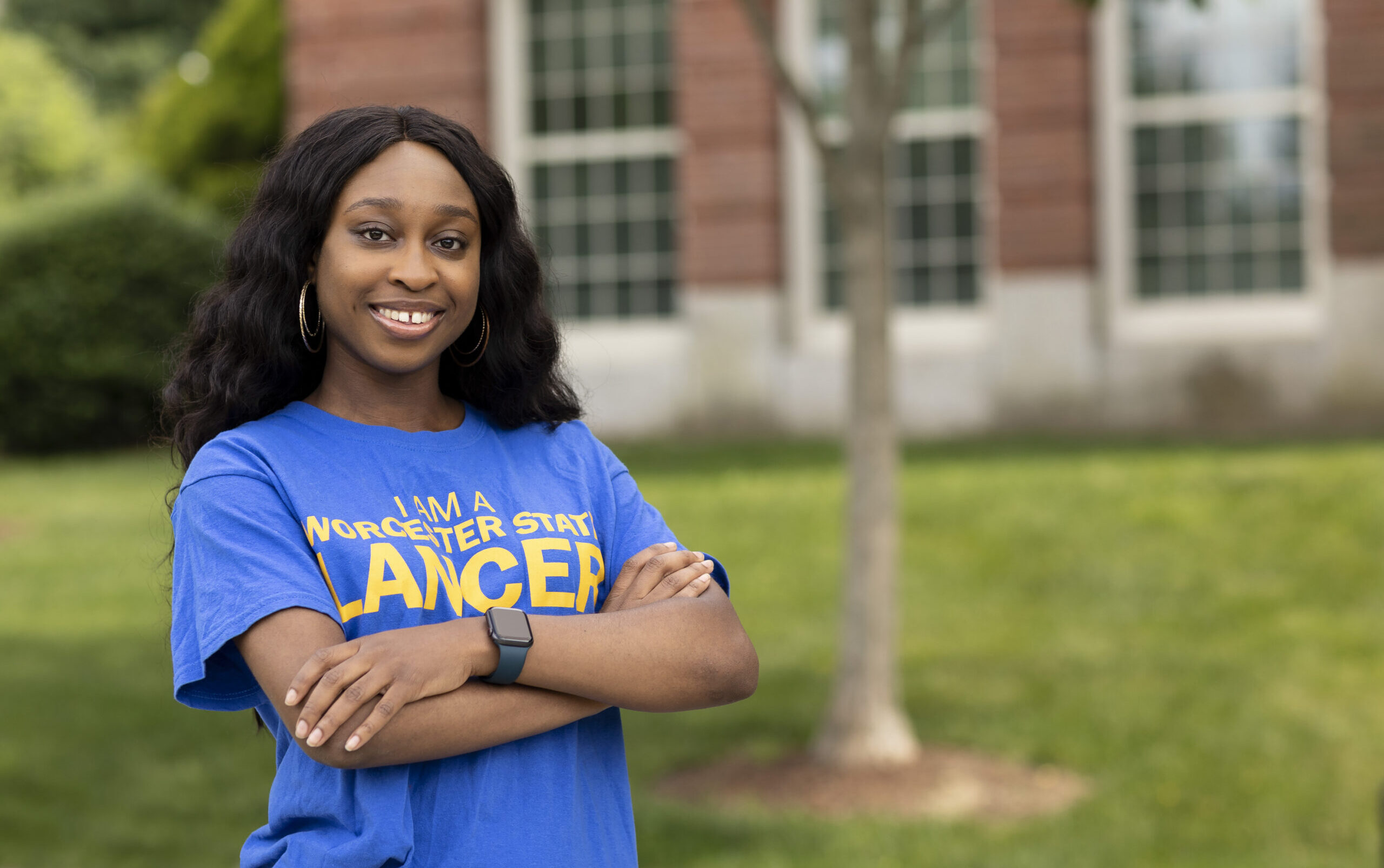 A proud Worcester state student posing for a picture on campus while wearing a Worcester State shirt