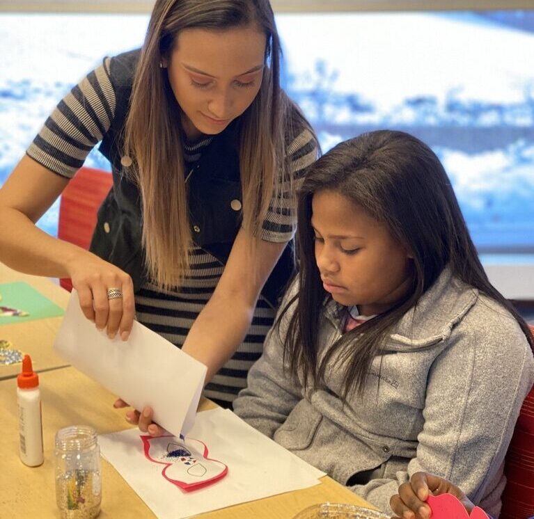 A Worcester state student helping a youth with their arts and crafts