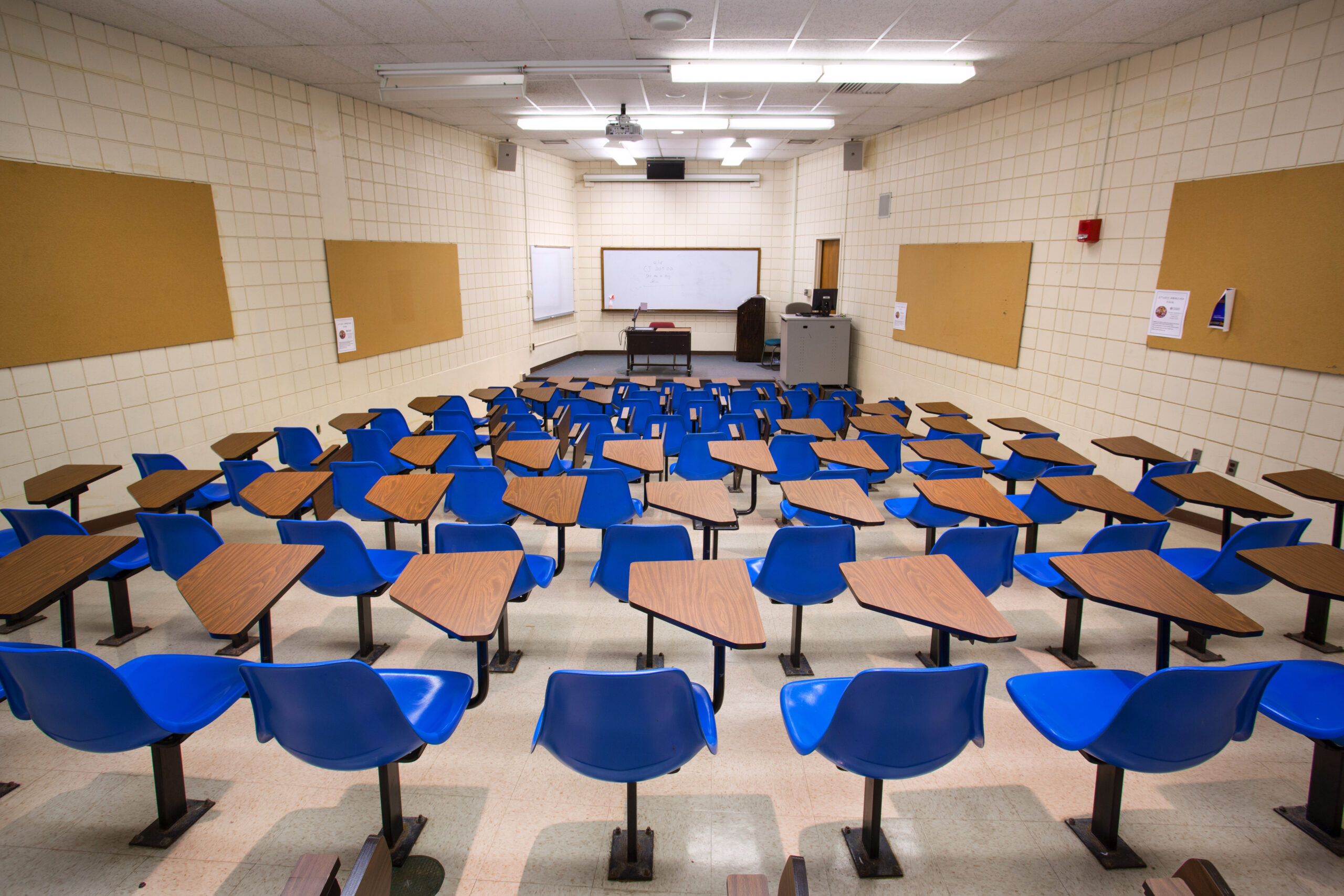 An empty Worcester State classroom filled with blue desks