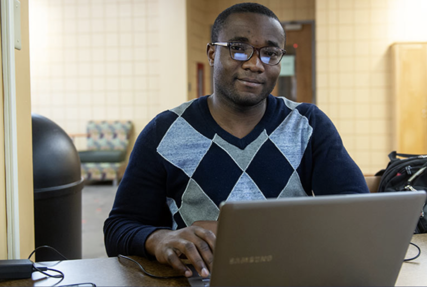 A Worcester State student working on a laptop on a campus