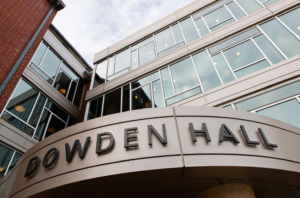 A modern building with large windows and a sign that reads "Dowden Hall.