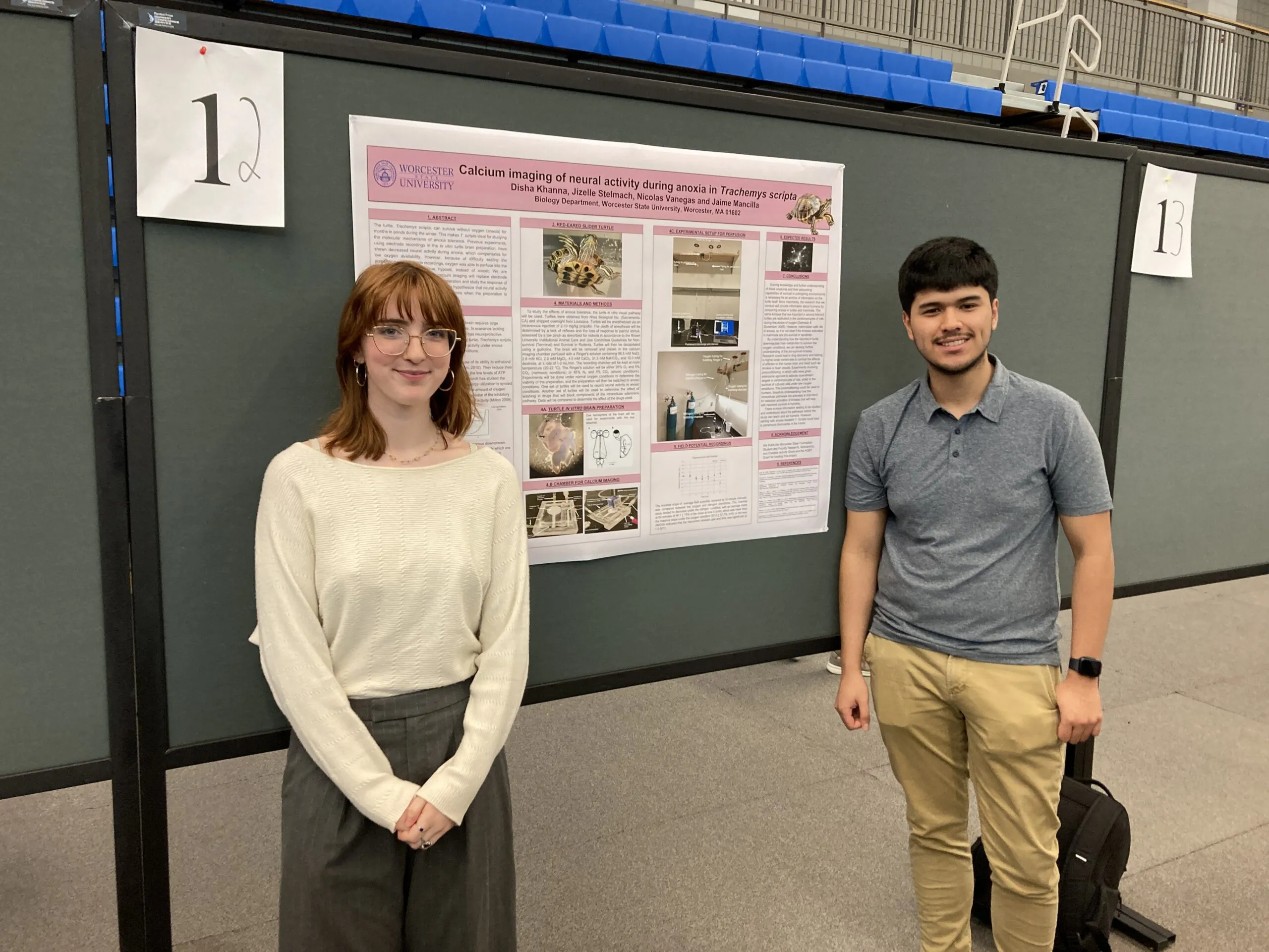 Two people stand in front of a scientific poster titled "Calcium imaging of neural activity during arousal in Trachemys scripta" at a presentation event.