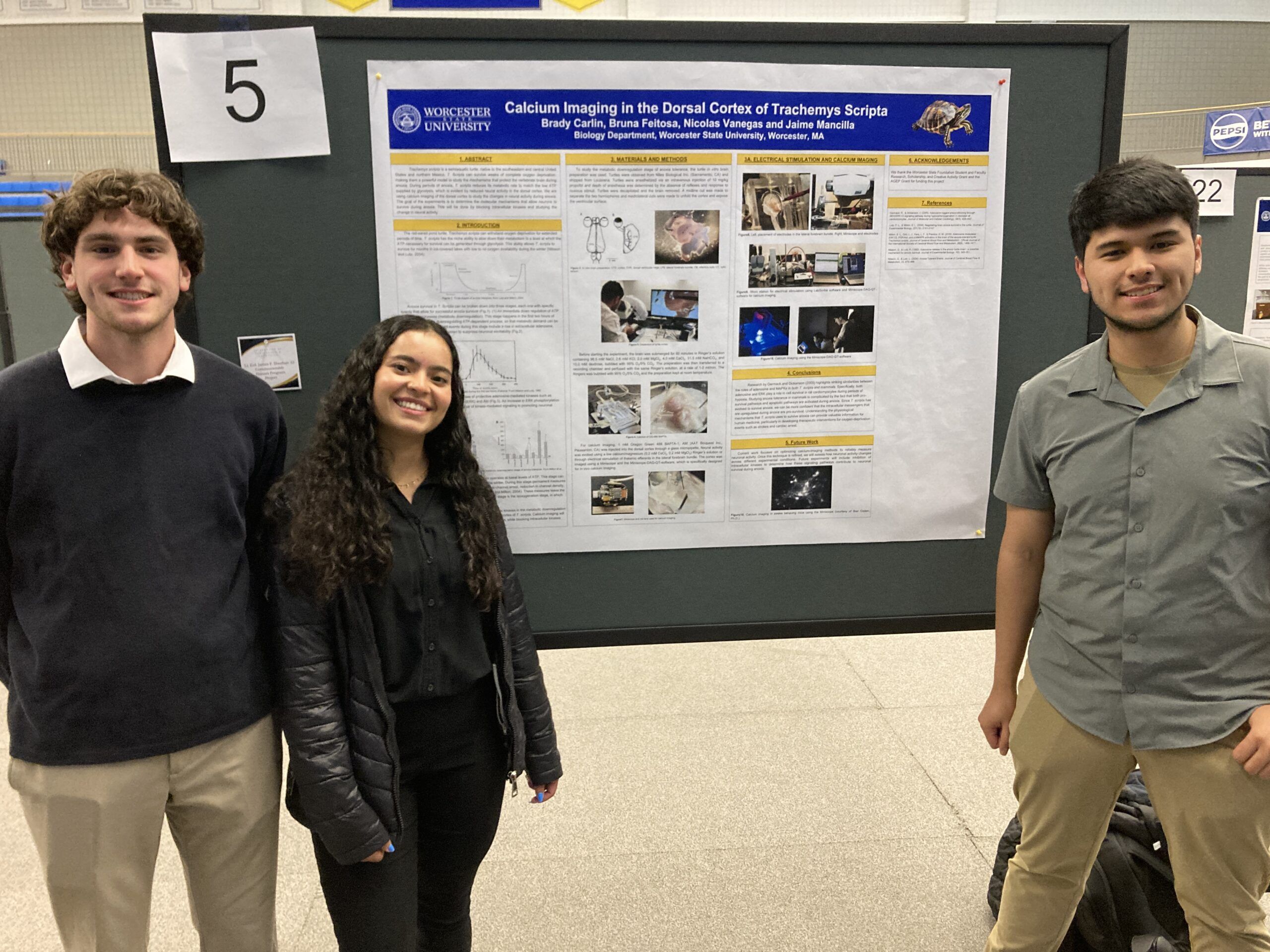 Three students stand in front of a scientific research poster titled "Calcium Imaging in the Dorsal Cortex of Trachemys Scripta" at a presentation event.