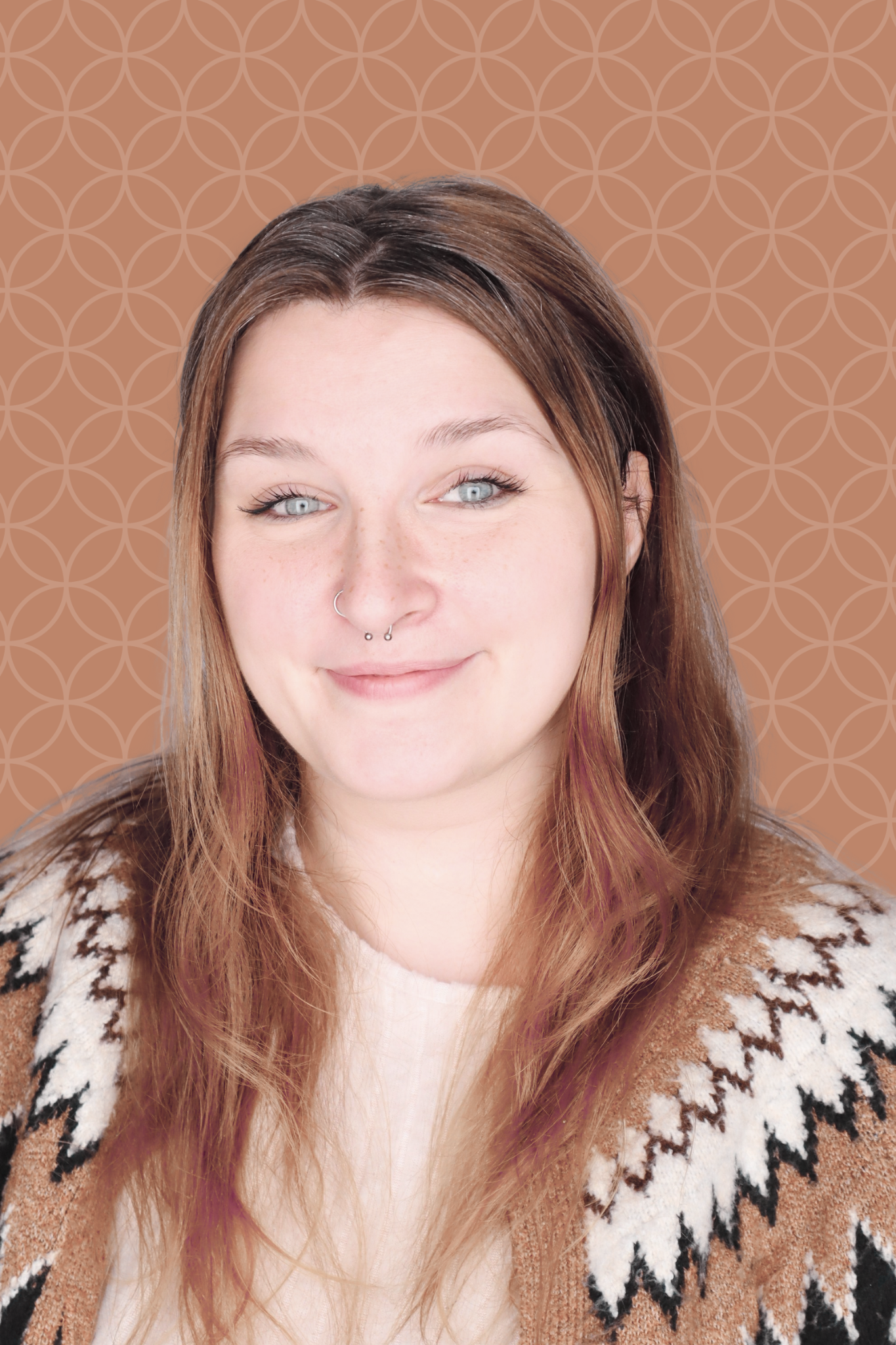 A woman with long brown hair and a patterned sweater smiles slightly in front of a geometric brown background.